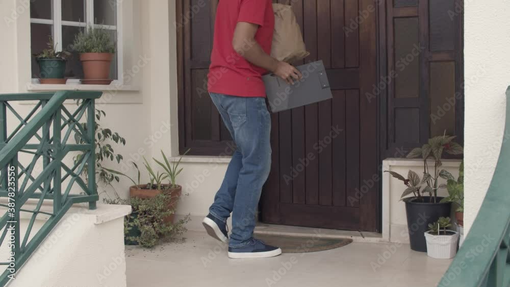 Courier leaving package with food at customers door and walking away. Cropped shot. Shipping or delivery service concept Courier leaving package with food at customers door and walking away. Cropped shot. Shipping or delivery service concept