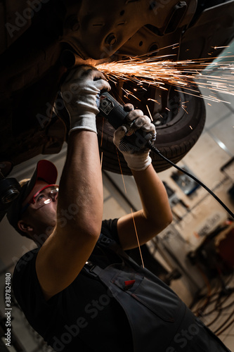 Mechanic working in the workshop under the car