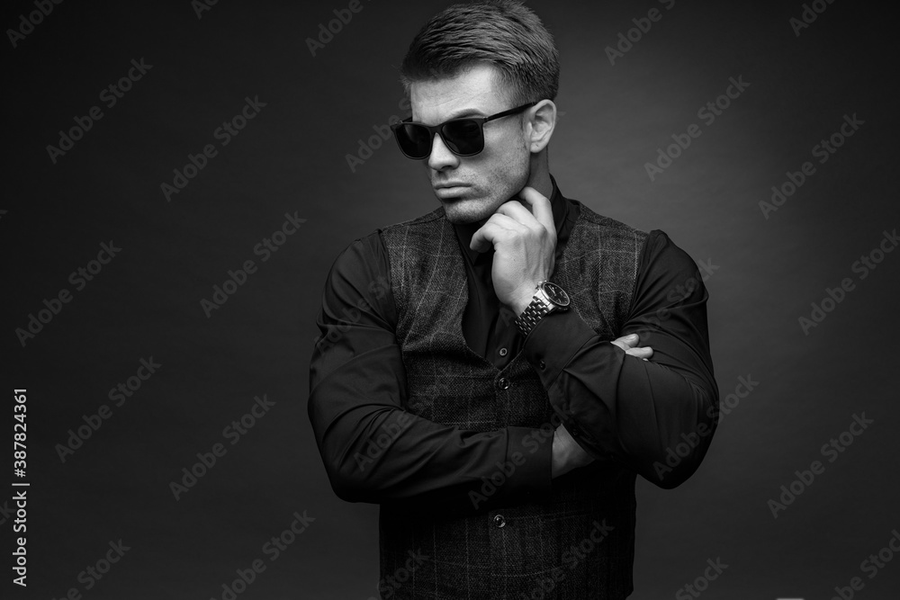 Black and white portrait of beautyful guy on dark background. High fashion model posing in studio. Attractive man in classic suit and sunglasses. Black and white portrait of beautyful guy on dark background. High fashion model posing in studio. Attractive man in classic suit and sunglasses.