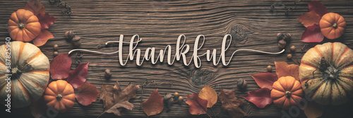  "Thankful" Message On Rustic Harvest Table Background Decorated With Pumpkins Acorns And Leaves 