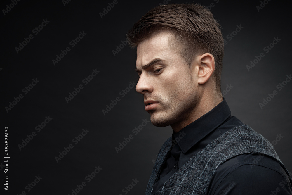 Portrait of beautyful guy on dark background. High fashion model posing in studio. Attractive man in classic suit.