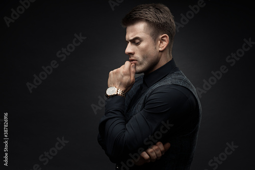 Portrait of beautyful guy on dark background. High fashion model posing in studio. Attractive man in classic suit.