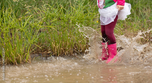 little girl in tutu skirt splashing in the puddle
