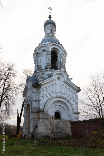 White and silver church belfry with green grass and cloudy sky in autumn day