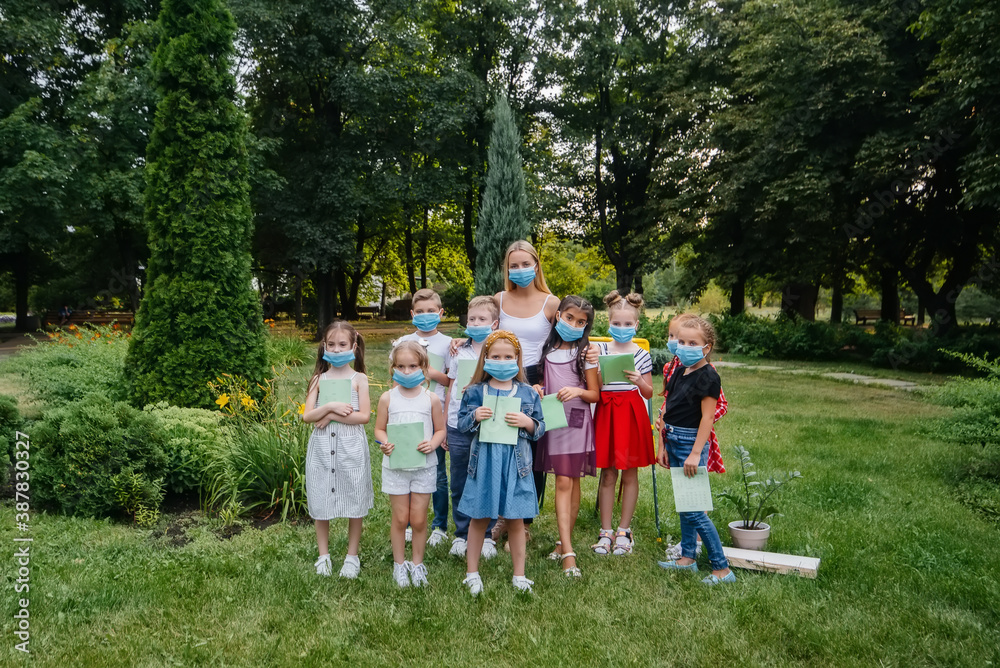 Obraz premium A class of masked school children is engaged in outdoor training during the epidemic. Back to school, learning during the pandemic