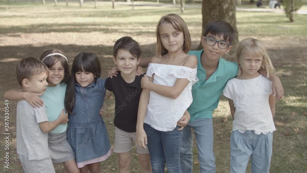 Multiethnic children standing together, hugging and smiling. Happy adorable boys and girls walking in city park, posing for photo and embracing. Childhood, friendship and summer vacation concept Multiethnic children standing together, hugging and smiling. Happy adorable boys and girls walking in city park, posing for photo and embracing. Childhood, friendship and summer vacation concept