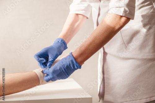 Doctor imposes an elastic bandage to the patient wrist. Rehabilitation after sprain