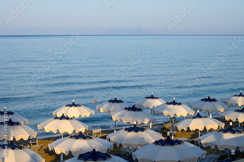Fototapeta Naklejka Na Ścianę i Meble -  Colorful parasols on sandy beach of medieval small touristic coastal town Sperlonga, Latina, Italy on sunrise