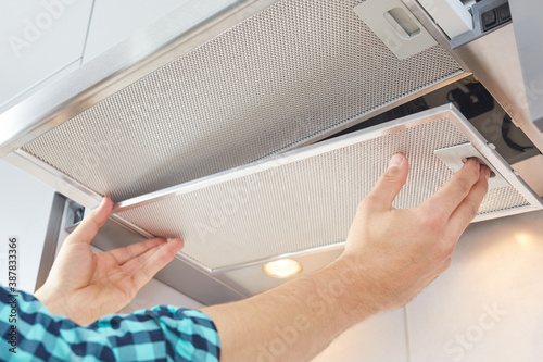 Foto Mans hands removing a filter from cooker hood for cleaning or service