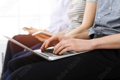 Group of casual dressed business people working at meeting or conference in sunny office  close-up of hands. Businessman using laptop computer