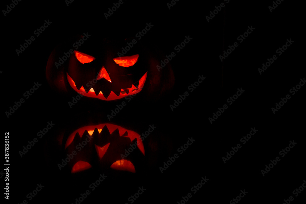 Hallowen pumpkin face glowing in the dark with reflection. Hallowen pumpkin face glowing in the dark with reflection.