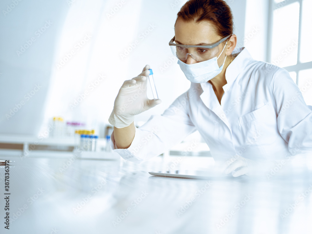 Female laboratory assistant analyzing a blood sample at hospital. Medicine, health care and researching concept Female laboratory assistant analyzing a blood sample at hospital. Medicine, health care and researching concept