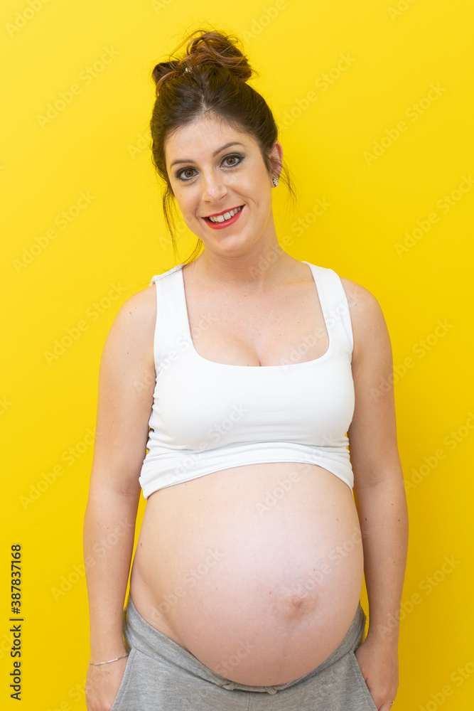 young pregnant woman smiling and a yellow background young pregnant woman smiling and a yellow background