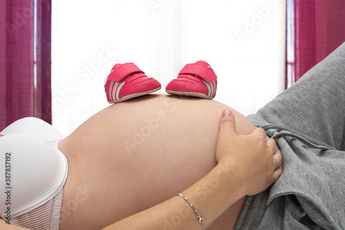 Pregnant woman's belly with baby shoes on it