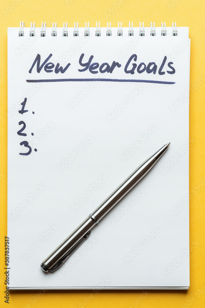 new year goals inscription in notebook on yellow background new year goals inscription in notebook on yellow background
