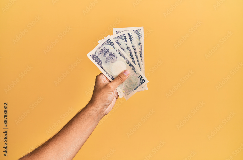 Ταπετσαρία Hand of hispanic man holding japanese yen banknotes over isolated yellow background