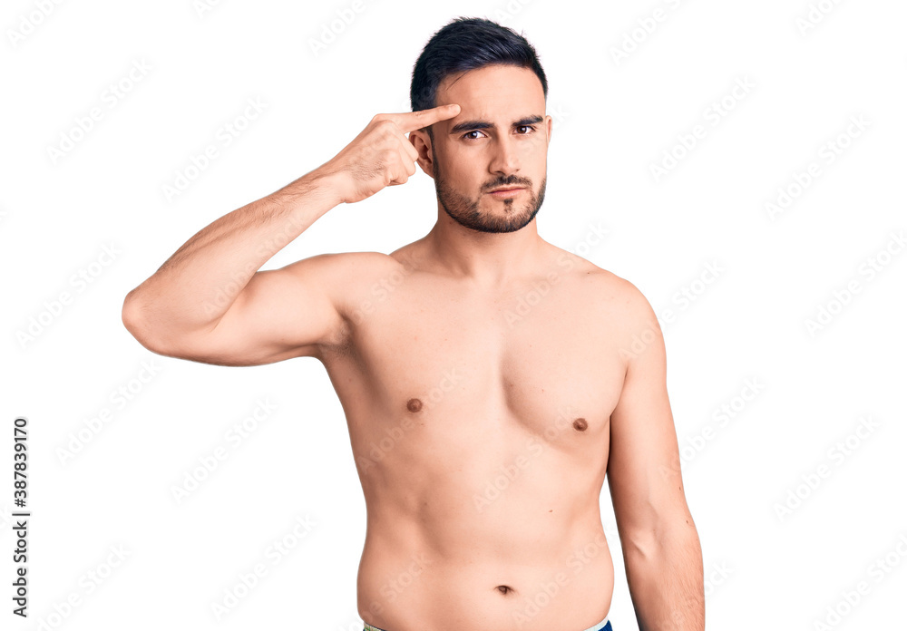 Fototapeta premium Young handsome man wearing swimwear pointing unhappy to pimple on forehead, ugly infection of blackhead. acne and skin problem