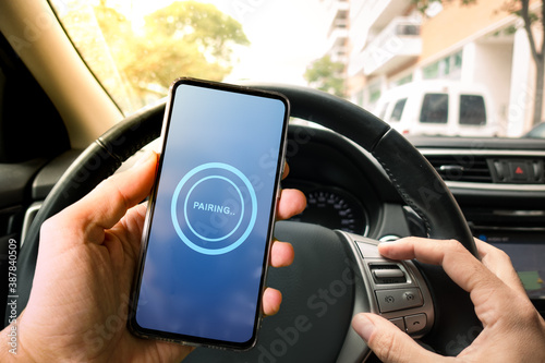 Pairing Smartphone with Car Multimedia Audio System. Using Mobile Phone Device While Driving. Hands Free Talking and Listening Online Music While Traveling by Car. photo