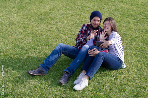 a guy and a girl on the lawn with a mobile phone