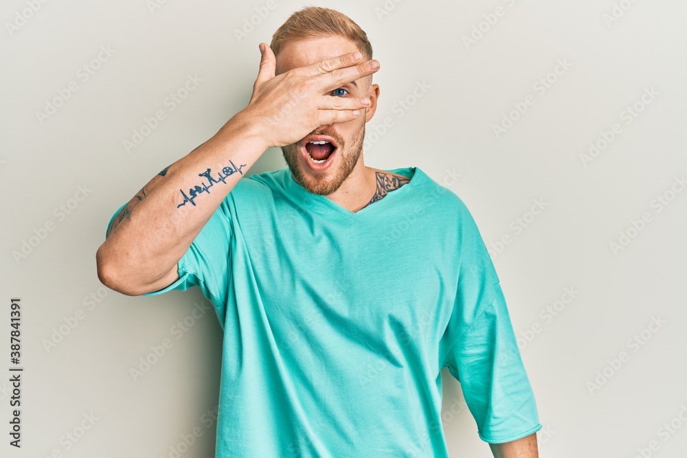 Young caucasian man wearing casual clothes peeking in shock covering face and eyes with hand, looking through fingers with embarrassed expression. Young caucasian man wearing casual clothes peeking in shock covering face and eyes with hand, looking through fingers with embarrassed expression.