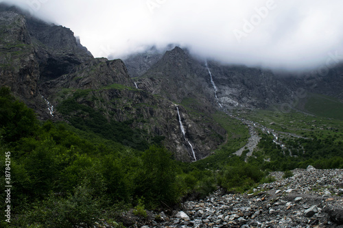 Midagrabindon waterfalls in the gorge. Mountains in the North Caucasus in summer. Mountain tops in the clouds.