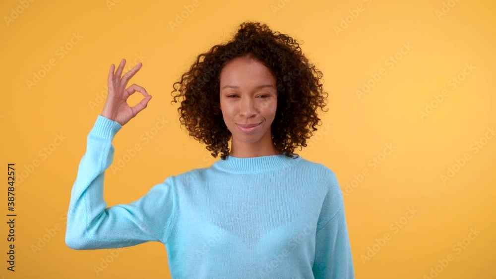 OK! Cute young mixed race woman on yellow background shows ok gesture. Isolated on a bright yellow background. 4K OK! Cute young mixed race woman on yellow background shows ok gesture. Isolated on a bright yellow background. 4K