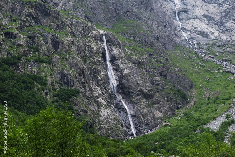 Midagrabindon  waterfalls in the gorge. Mountains in the North Caucasus in summer. Mountain tops in the clouds.