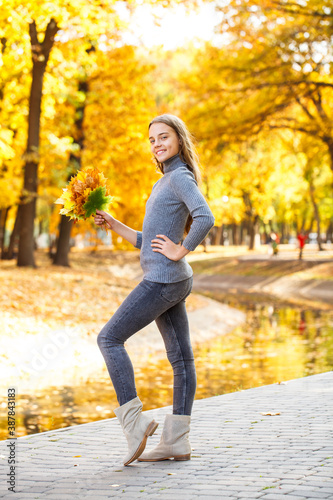 Full length portrait of a young beautiful girl posing in an autumn park
