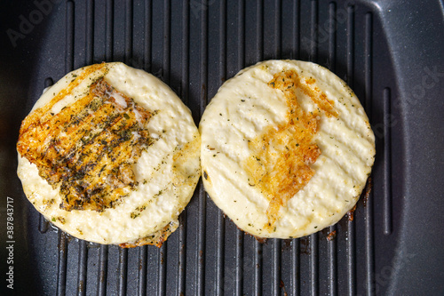 delicious pieces of halumi cheese cooking on a hot iron stove with smoke coming out photo