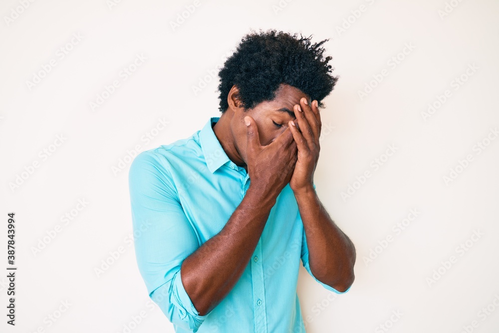 Handsome african american man with afro hair wearing casual clothes with sad expression covering face with hands while crying. depression concept. Handsome african american man with afro hair wearing casual clothes with sad expression covering face with hands while crying. depression concept.