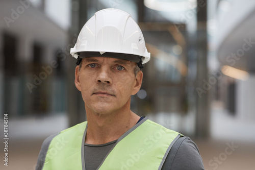 Close up portrait of professional construction worker looking at camera while standing on construction site, copy space