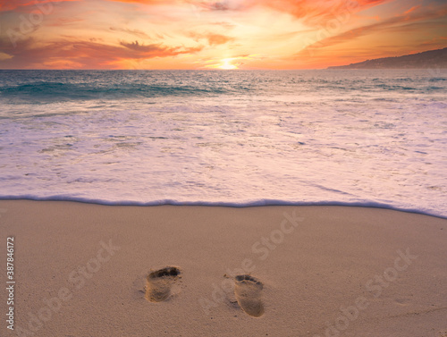 foot steps in sandy beach with sunset