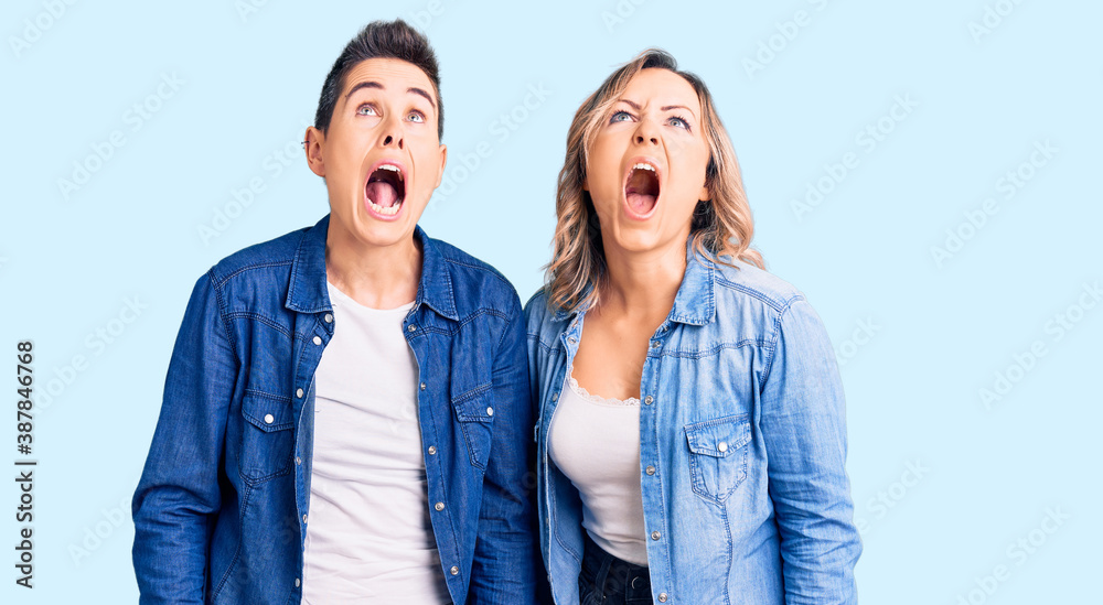 Couple of women wearing casual clothes angry and mad screaming frustrated and furious, shouting with anger. rage and aggressive concept. Couple of women wearing casual clothes angry and mad screaming frustrated and furious, shouting with anger. rage and aggressive concept.