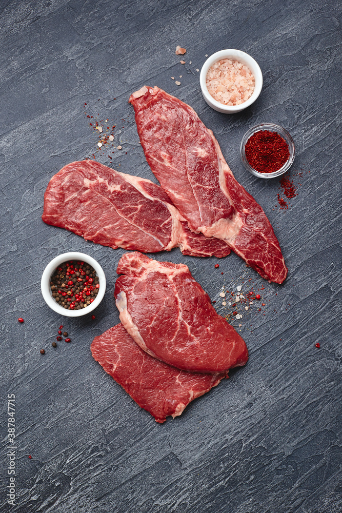 Raw meat beef steak on black top view.