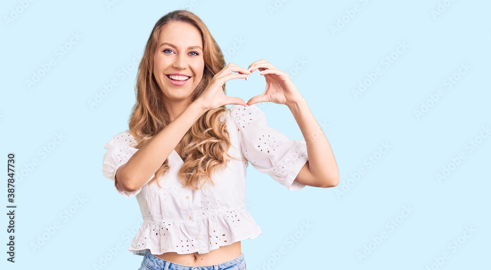 Young caucasian woman with blond hair wearing elegant summer tshirt smiling in love showing heart symbol and shape with hands. romantic concept. Young caucasian woman with blond hair wearing elegant summer tshirt smiling in love showing heart symbol and shape with hands. romantic concept.