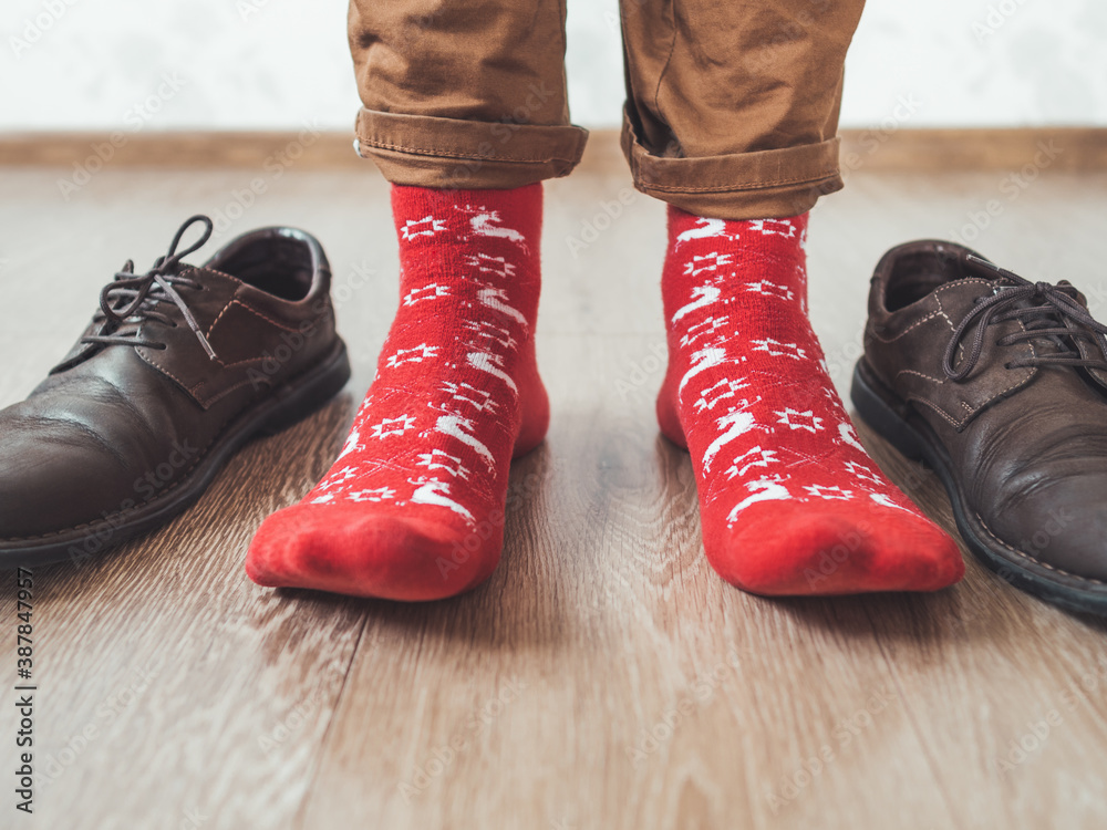 Young man in chinos trousers and bright red socks with reindeers on them is  ready to
