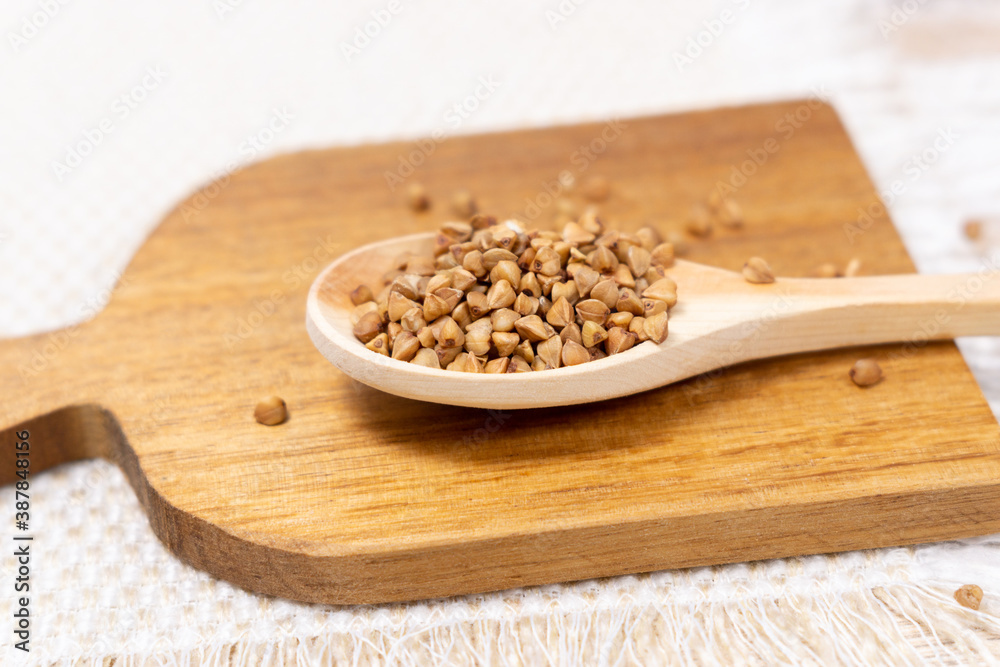 raw buckwheat grain on a wooden spoon on wood table background. selective focus raw buckwheat grain on a wooden spoon on wood table background. selective focus