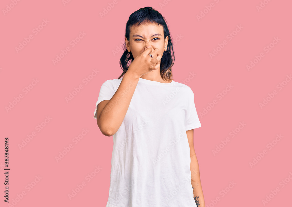 Young woman wearing casual clothes smelling something stinky and disgusting, intolerable smell, holding breath with fingers on nose. bad smell Young woman wearing casual clothes smelling something stinky and disgusting, intolerable smell, holding breath with fingers on nose. bad smell