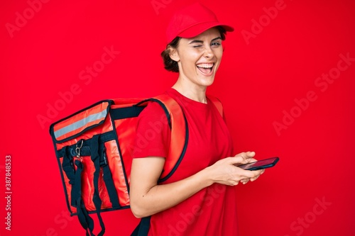 Young hispanic woman holding delivery box calling assistance winking looking at the camera with sexy expression, cheerful and happy face.