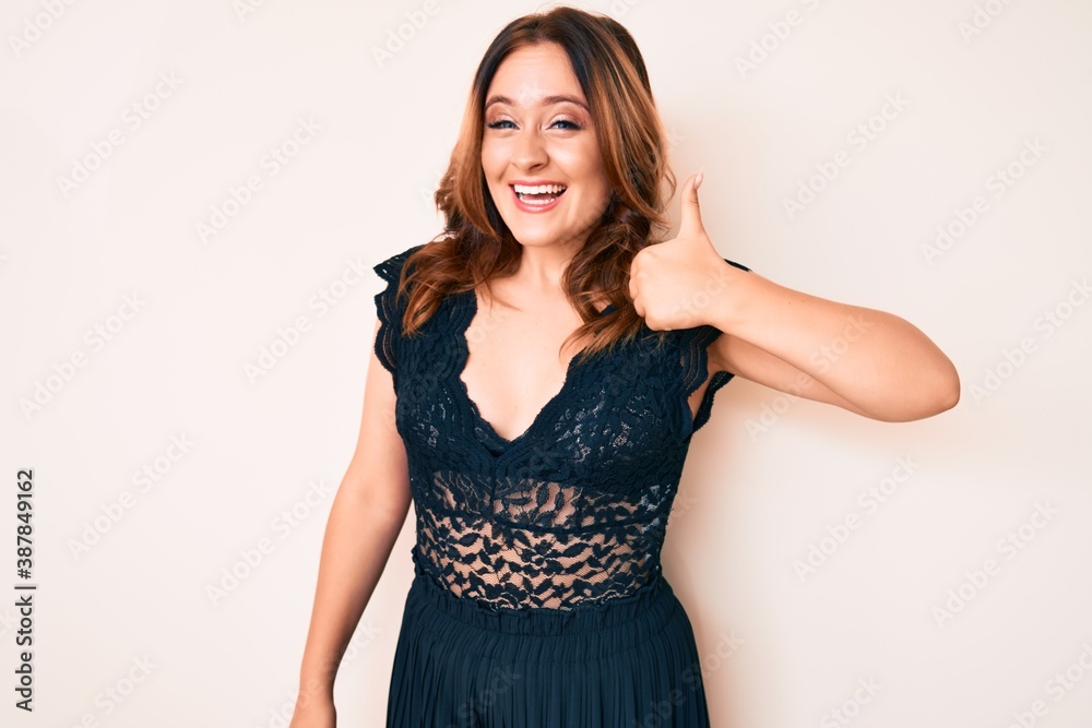Young beautiful caucasian woman wearing elegant clothes smiling happy and positive, thumb up doing excellent and approval sign Young beautiful caucasian woman wearing elegant clothes smiling happy and positive, thumb up doing excellent and approval sign