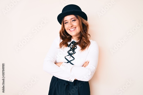 Young beautiful caucasian woman wearing elegant style and hat happy face smiling with crossed arms looking at the camera. positive person.