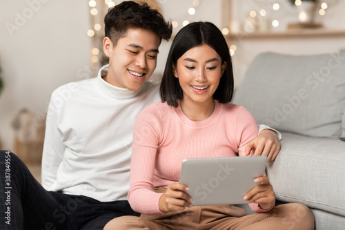 Asian Couple Using Tablet Computer Watching Movie Online At Home