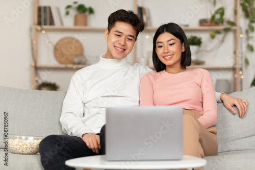 Asian Family Couple Watching Movie On Laptop Online At Home
