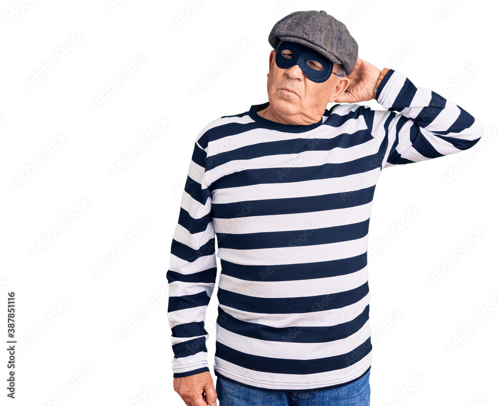 Senior handsome man wearing burglar mask and t-shirt confuse and wondering about question. uncertain with doubt, thinking with hand on head. pensive concept.