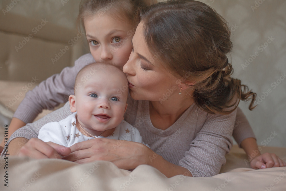 Mother holding infant baby, take care of her 3 months old child at home bedroom . Happy mom carying of her newborn son . Mother and elder sister kissing the boy Mother holding infant baby, take care of her 3 months old child at home bedroom . Happy mom carying of her newborn son . Mother and elder sister kissing the boy