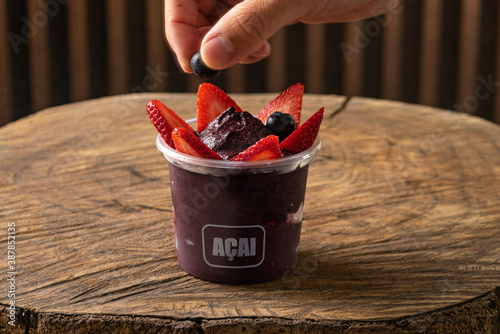 Delicious Brazilian Açaí Cream, in a plastic Cup With Strawberry and blueberry Topping. Summer acai smoothie