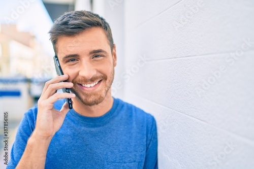 Young caucasian man smiling happy talking on the smartphone at the city.