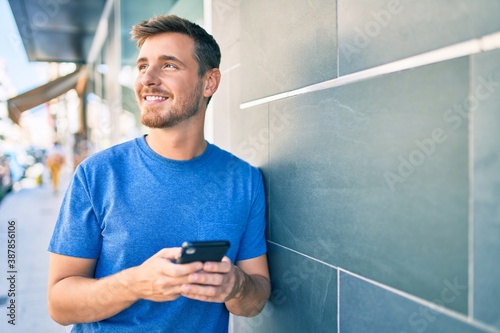 Young caucasian man smiling happy using smartphone at the city. © Krakenimages.com