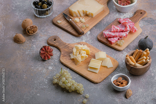 Assorted cheese, salumi, nuts on wooden boards, copy space
