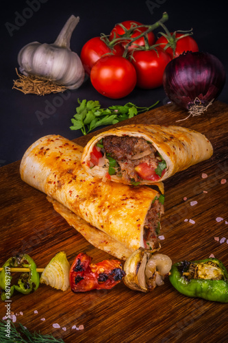 Turkish and Arabic Traditional Ramadan Adana Kebab Roll Wrap serving with yogurt  aubergine salad and hot pepper pickles on rustic wooden background.